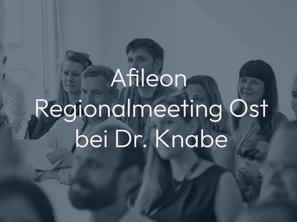 Eine Gruppe von Menschen sitzt in einem Konferenzraum und hört aufmerksam bei einer Besprechung zu, während der Titel des Meetings "Afileon Regionalmeeting Ost bei Dr. Knabe" prominent im Vordergrund steht.
