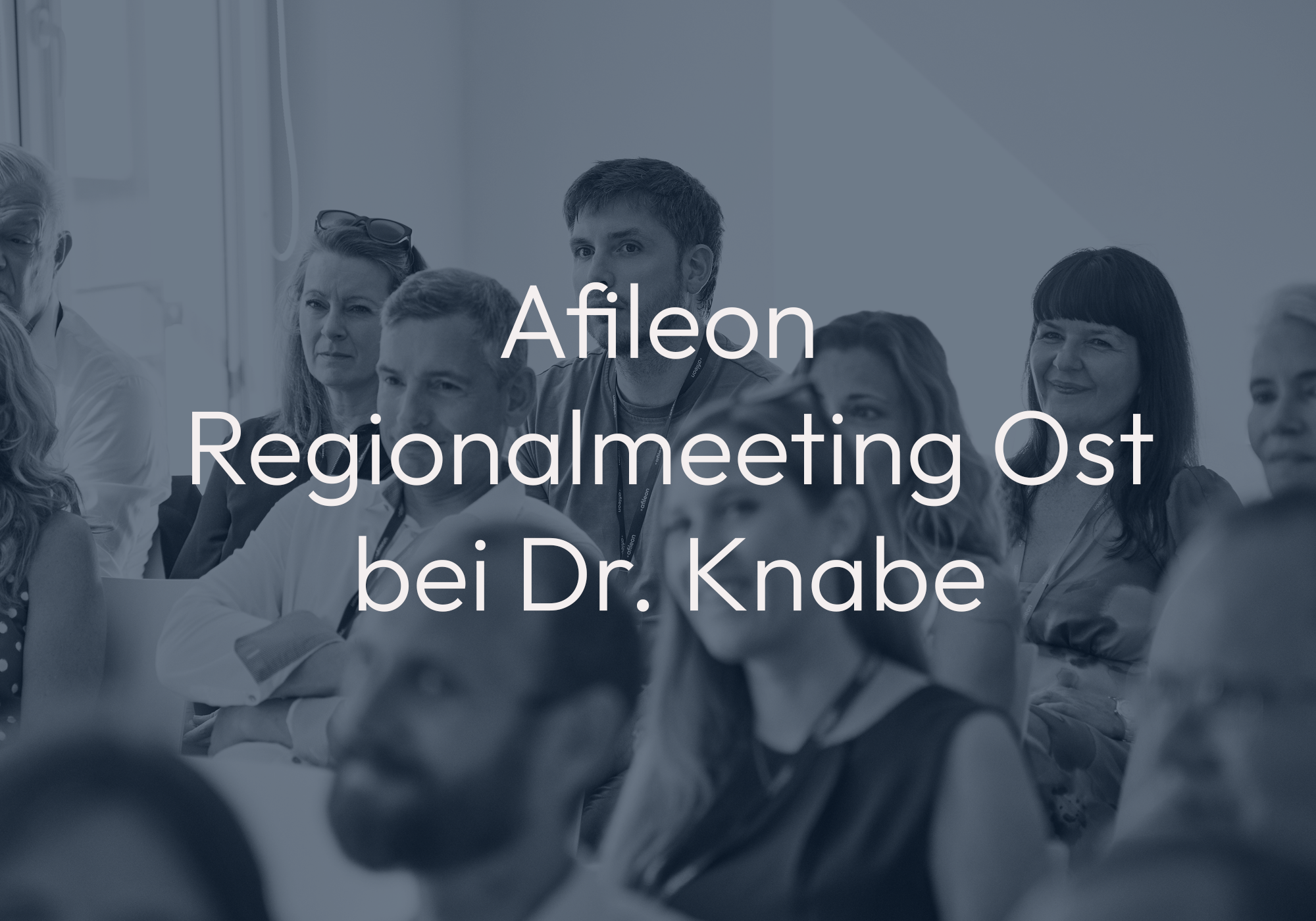 Eine Gruppe von Menschen sitzt in einem Konferenzraum und hört aufmerksam bei einer Besprechung zu, während der Titel des Meetings "Afileon Regionalmeeting Ost bei Dr. Knabe" prominent im Vordergrund steht.